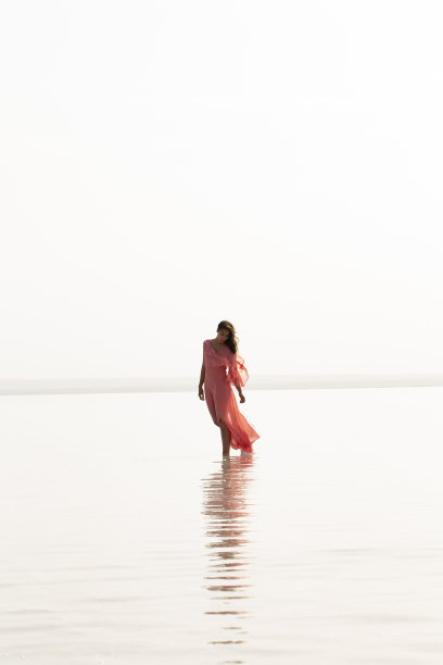 日落时分在海上散步的女人。海滩暑假度假旅游放松概念图片下载