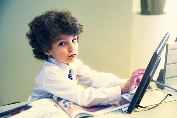 一个小商人正坐在工作场所，桌上放着一台平板电脑图片下载