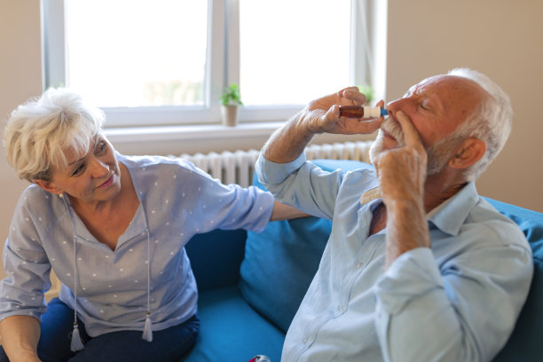 当她们坐在客厅的沙发上时，一位老妇人帮助生病的丈夫。她给他吃药，照顾他。图片下载