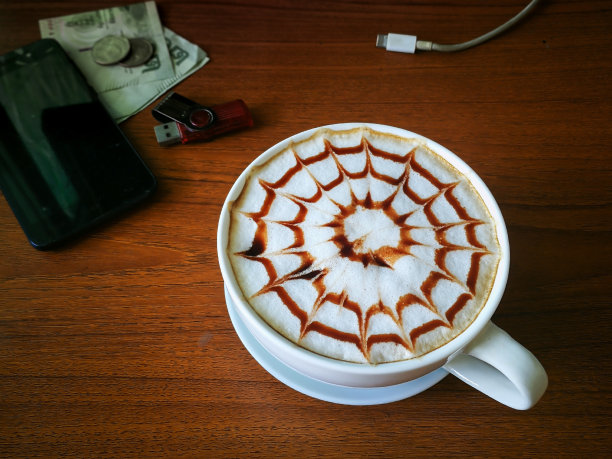 咖啡杯拉花艺术与巧克力酱和焦糖酱牛奶泡沫桌上木制图案图片下载