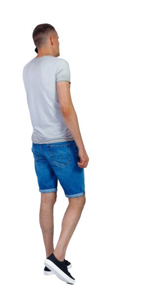 后视图的男人在短裤行走与手机。图片下载