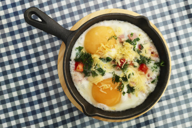 用平底锅煎蛋，加上洋葱和奶酪。新鲜的，美味的鸡蛋和蔬菜图片下载