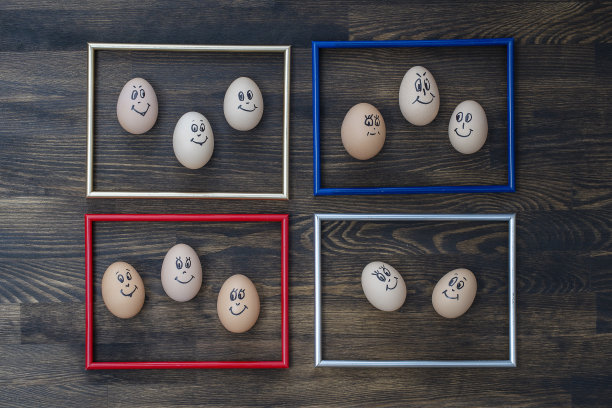 画框和许多有趣的鸡蛋微笑在黑暗的木墙背景。鸡蛋家庭情感面部肖像。概念有趣的食物图片下载