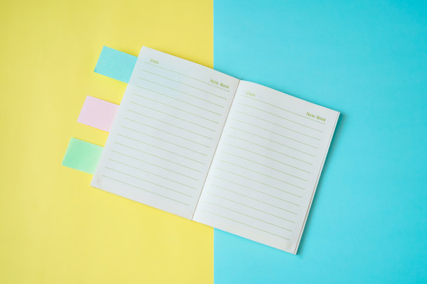 顶视图打开的笔记本与蓝色和黄色的纸背景图片下载