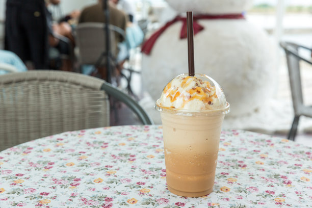 桌上有冰咖啡和奶油。咖啡店的焦糖冰沙咖啡。冰混合推广。塑料外带的星冰乐或者咖啡馆的木桌上的外带杯图片下载
