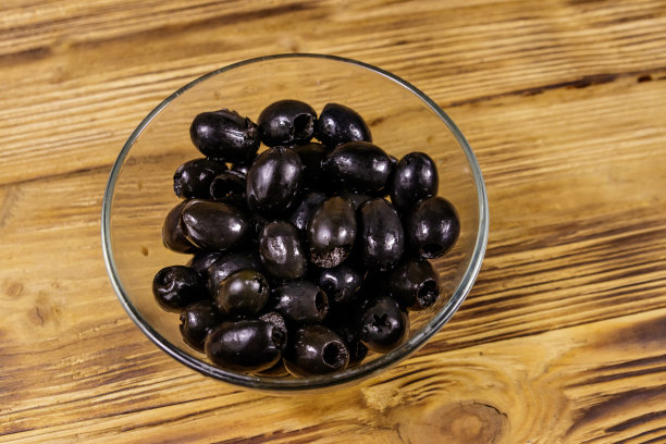 腌黑橄榄放在木桌上的玻璃碗里图片下载