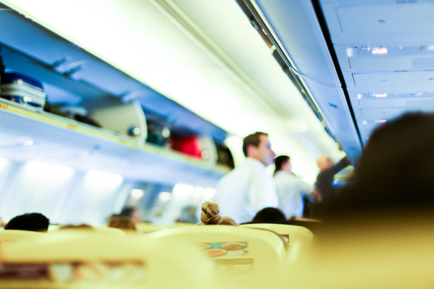 模糊的飞机内部照片，乘务员和乘客的行李在架子上图片下载