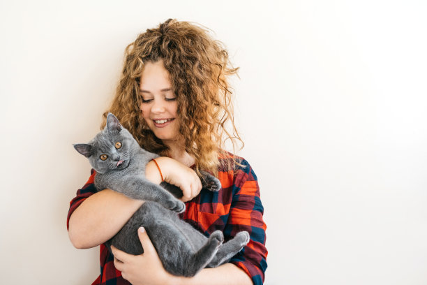 卷毛的金发少女微笑着，手里拿着一只灰色的小猫图片下载