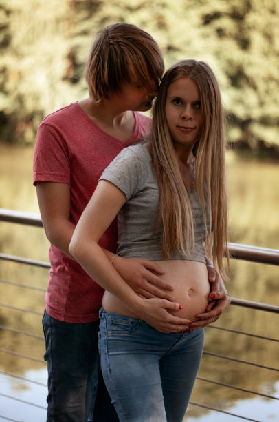 竖版照片：幸福的孕妇夫妇在湖边公园散步图片下载