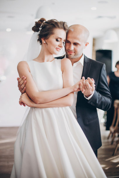 华丽的新娘和新郎在餐厅婚宴上温柔的拥抱和跳舞。美丽时尚的新婚夫妇表演第一支舞蹈和拥抱。感性浪漫的时刻图片下载