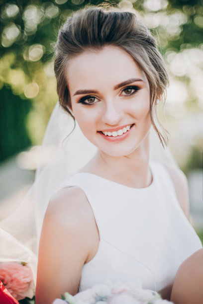 美丽幸福的新娘穿着白色礼服，时髦的发型和面纱微笑在夏天的公园。性感的肖像美丽的新娘户外图片下载