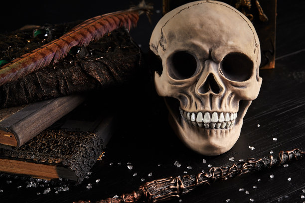 一个有牙齿的人类头骨模型放在一张黑色木头桌子上，黑色的背景。医学或者万圣节恐怖概念特写镜头图片下载
