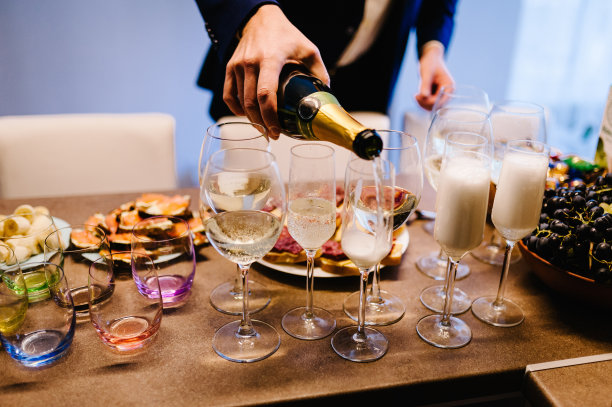 男人把香槟倒进酒杯里。香槟倒进玻璃杯里。图片下载