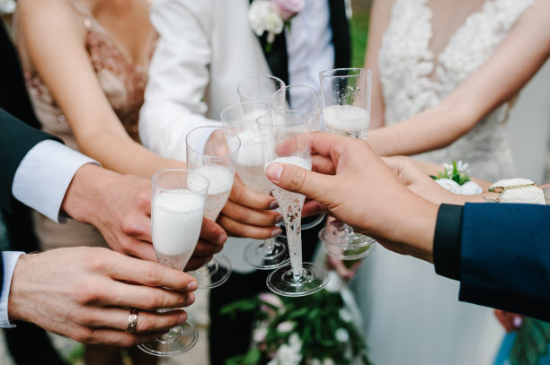 干杯!新婚夫妇和朋友在户外喝香槟。人们举杯庆祝，举杯祝酒。一群男女庆祝婚礼。图片下载
