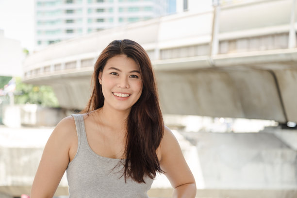 肖像图片迷人美丽的亚洲长发女人微笑着看着相机在灰色背心，图片下载