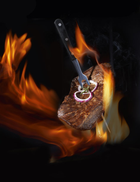 飞行热烤牛排牛肉与迷迭香，胡椒和盐叉子与明火。烧烤和烹饪。背景上有自由的文字空间设计或标识式菜单餐厅。水平的照片。食品的背景。概念:黑色文本区。休息图片下载