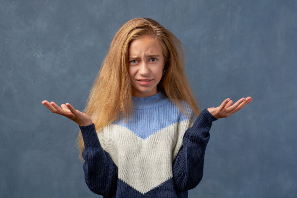 十几岁的金发女孩在温暖的毛衣孤立的墙图片下载