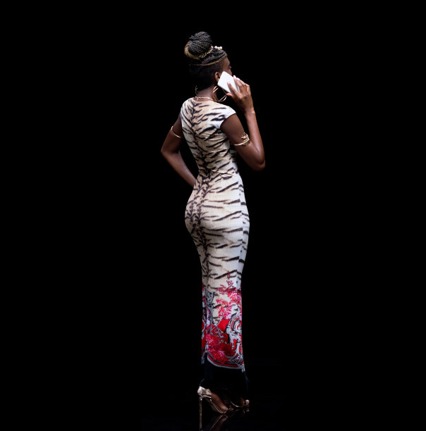 全长/后视图/后视图/一个20-29岁的成年人漂亮的黑发/长发非洲裔/非洲裔女性/年轻女性站在黑色背景下穿着长裙/裙子谁在说话图片下载