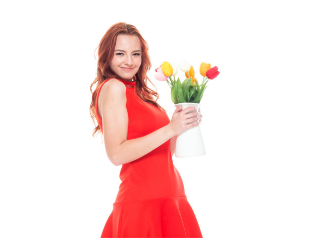 一个人/腰部以上的18-19岁美丽的红发白人年轻女性十几岁的女孩在白色的背景穿着裙子和高跟鞋谁是微笑/快乐/愉快的，手持郁金香/花/植物/浪漫图片下载
