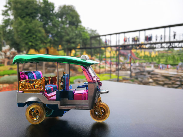 纪念品迷你嘟嘟车在黑色表面桌子或道路和模糊公园为背景。泰国曼谷的传统出租车。图片下载