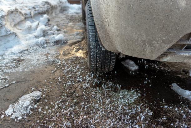 冬季轮胎钉在前面的越野车站在冬天的冰与雪和反射阳光在黎明。图片下载