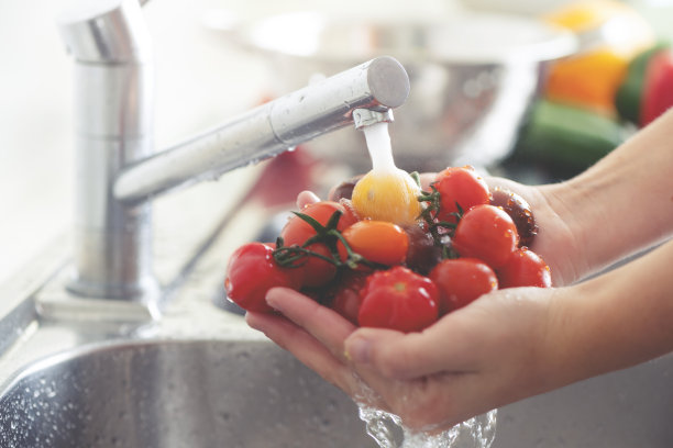 在水槽里洗西红柿的女人。图片下载