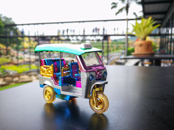 纪念品迷你嘟嘟车在黑色表面桌子或道路和模糊公园为背景。泰国曼谷的传统出租车。图片下载