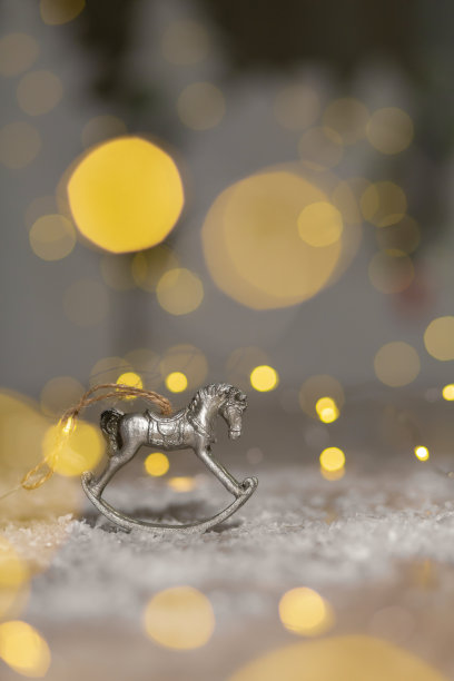 圣诞主题的装饰小雕像。摇摆木马的小雕像。装饰圣诞树。节日装饰，温馨的散景灯图片下载