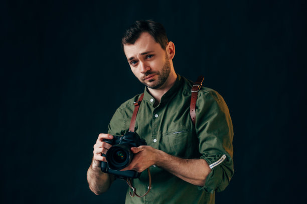 一个脖子上挂着数码相机，微笑着看相机的帅哥图片下载