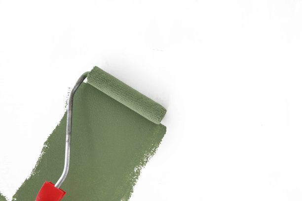 油漆滚筒。在白墙上涂绿漆的工艺。图片下载