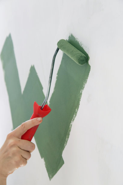 油漆滚筒。在白墙上涂绿漆的工艺。图片下载