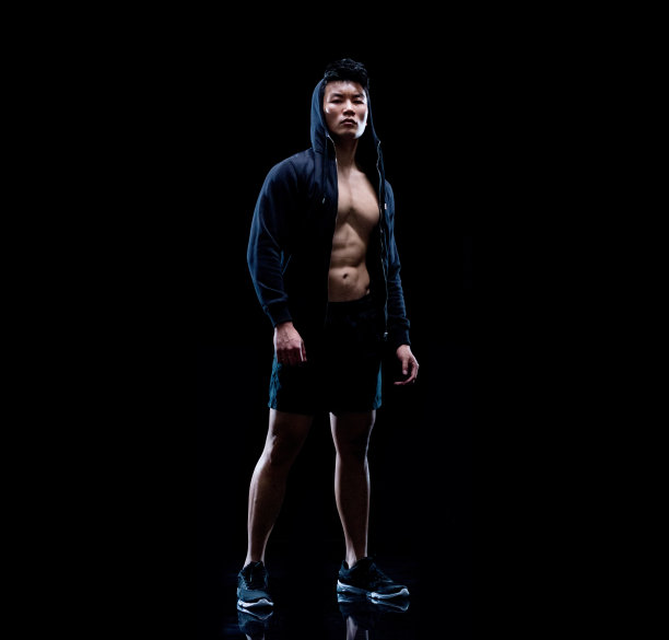 一个男人/一个人/全长30-39岁的成年人英俊的人黑头发中国民族/东亚民族青年男子/男性站在黑色背景/黑色颜色/背光图片下载