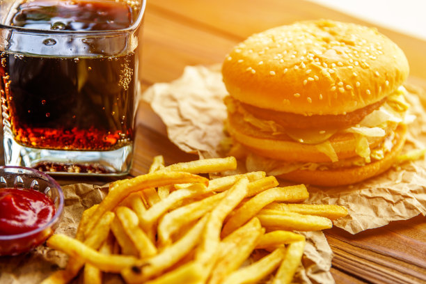 牛皮纸上的汉堡，薯条和汽水，木质背景图片下载