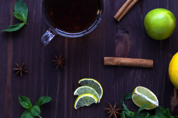 健康的生活方式。柠檬和柠檬，一杯红茶与绿色薄荷和肉桂在一个木制的背景俯视图。图片下载