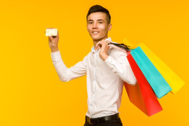 年轻的亚洲男子展示他的购物袋和信用卡图片下载