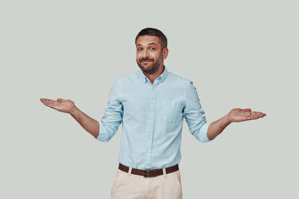 帅气的年轻人站在灰色的背景下，看着镜头，伸出手臂图片下载