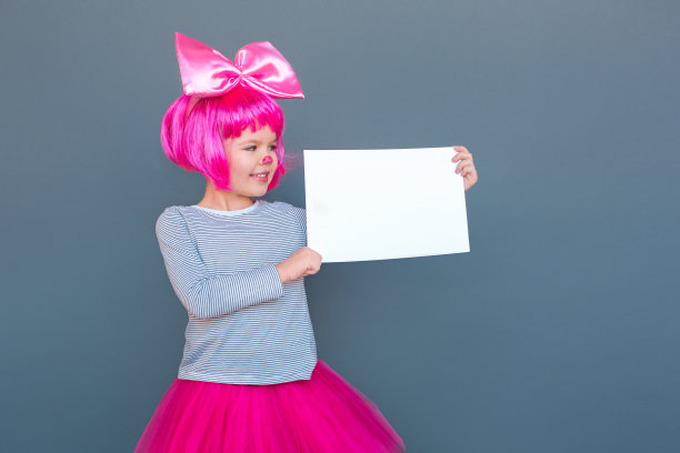 漂亮的小女孩穿着小丑服装拿着白色的桌子图片下载