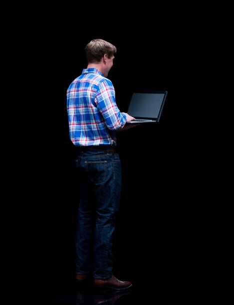 全长/后视图/背部/一个男人/一个20-29岁的成年人英俊的人白人男性/年轻男子站在黑色背景穿着纽扣衬衫/衬衫/牛仔裤/裤子/伐木工衬衫/格子衬衫图片下载