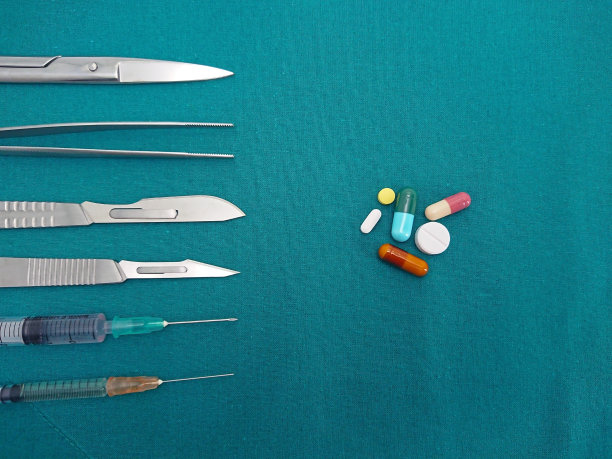 带注射器的外科器械和药片，药片和胶囊放在外科绿色悬垂布上图片下载
