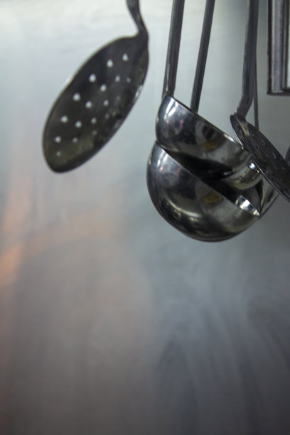 不锈钢厨房用具挂在烘干机的专业厨房。图片下载