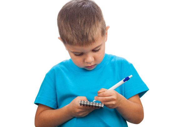 一个5岁的学前班小男孩在一个笔记本上写着一支笔，孤立在白色的背景上图片下载