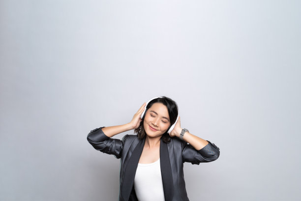 快乐的女人戴着耳机，在白色的背景下听音乐图片下载