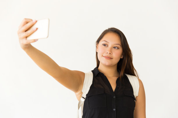 微笑的女人用智能手机自拍图片下载