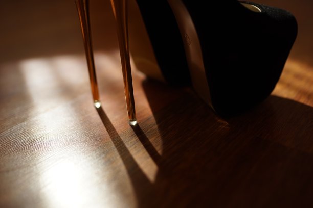 黑人妇女穿着高跟鞋走在光亮的棕色拼花地板上。图片下载