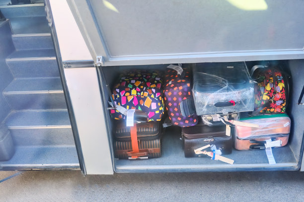 巴士的货舱里有红色和黑色的行李箱。旅行箱里的行李准备出发。堆放在公共汽车行李厢里的行李箱图片下载