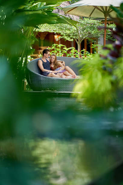在巴厘岛，一对年轻的白人夫妇懒洋洋地躺在豪华的热带酒店和水疗中心附近的现代椅子上图片下载