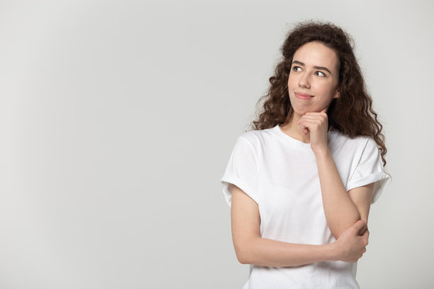 愉快的，体贴的，微笑的年轻女子看一边的拷贝空间。图片下载