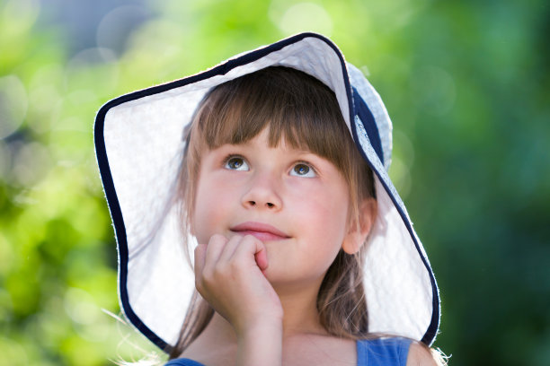 特写的快乐微笑的小女孩戴着一顶大帽子。孩子在户外玩耍的时间在夏天。图片下载