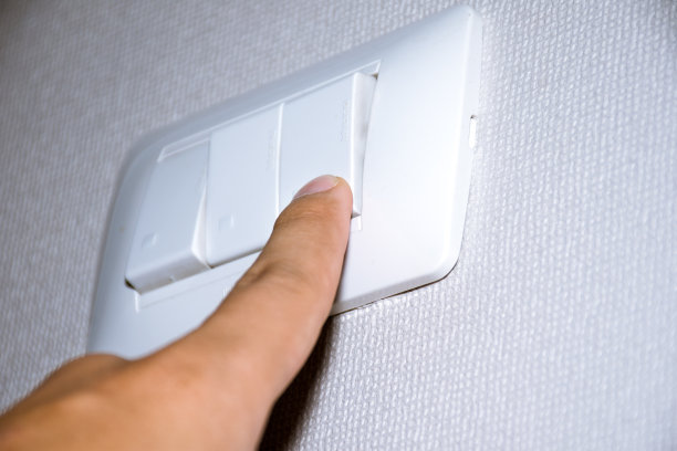 男人的手正在打开或关闭电灯开关。图片下载