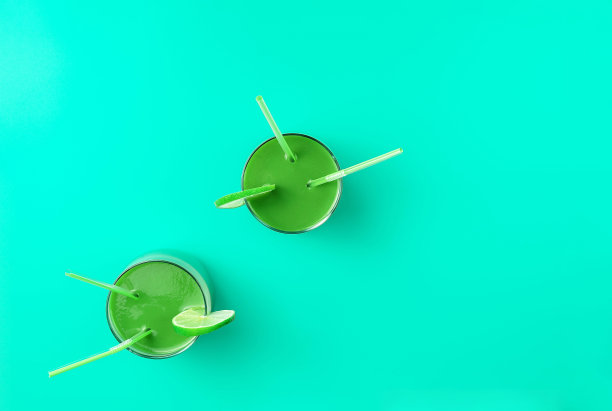 两杯健康的绿色奶昔，配上装饰着酸橙的鸡尾酒吸管。饮食、节食和营养概念。平的背景。图片下载